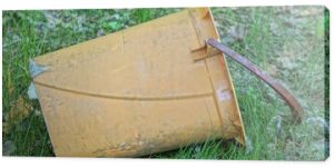 one large brown old plastic bucket dry closet stands in the green grass on the street