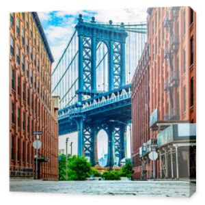 Manhattan Bridge między Manhattanem a Brooklynem nad East River widziany z wąskiej uliczki otoczonej dwoma ceglanymi budynkami na su