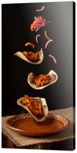 Creative food image of Mexican Tacos de Cochinita Pibil and onion with habanero chili falling on traditional mexican clay dish. Levitation photography.