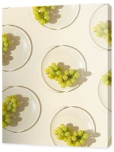 Food pattern from bunch white grapes on glass plate with shadows at sunlight, minimal style summer fruit on beige colored fon, green berries of grape, top view, trend flat lay, food