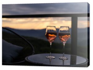 Two glasses of wine standing with a beautiful scenic mountain view. Mountain resort, enjoy moment