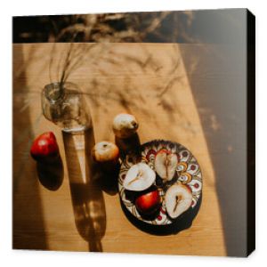 still life with a bottle. pears on a wooden table. pears on a wooden table bathed in the sun. picnic in the summer garden. flowers and fruits on a wooden table. sunny shadows on the kitchen table