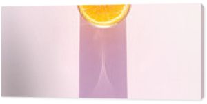 Glass of drink with orange on a pink background. Aesthetic long shadow glass summer concept.