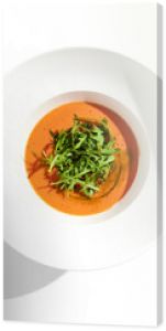 Summer Spanish soup - gazpacho with rocket salad isolated on white background. Vegetarian cold tomato soup in white plate. Meatless food in menu. Veggie lunch. Healthy food. Plant based eating.