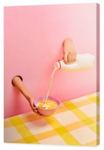 Food pop art photography. Female hands sticking out pink paper, pouring milk into bowl with corn flakes, ceral. Breakfast. Taste, creativity, art. Complementary colors. Copy space for ad, text