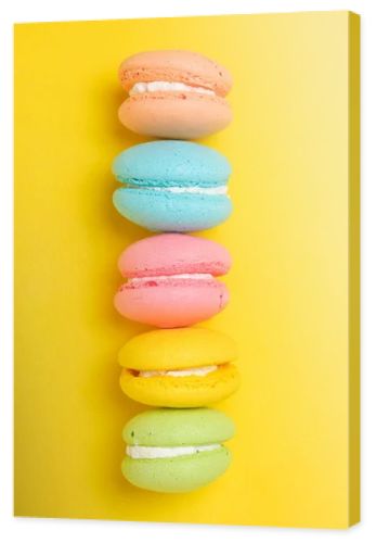 Colorful and bright French macarons cookies on yellow background