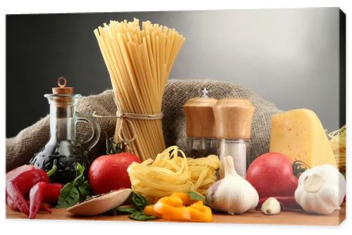Pasta spaghetti, vegetables and spices, on wooden table, on grey background