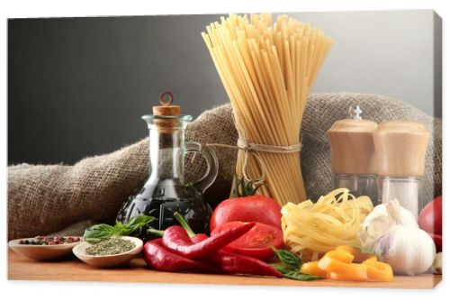 Pasta spaghetti, vegetables and spices, on wooden table, on grey background