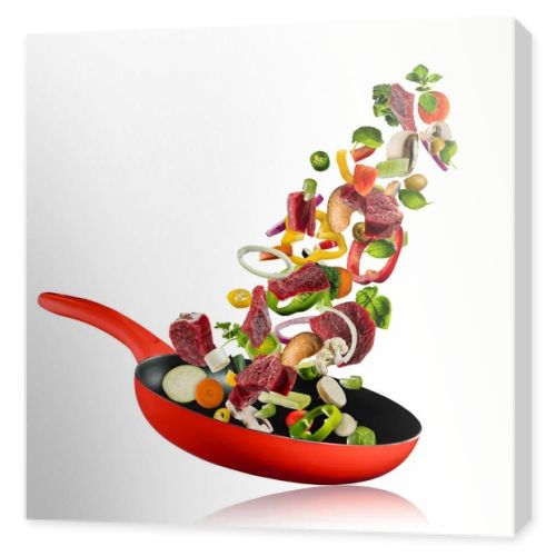 Fresh vegetables and beef meat flying into a pan on white background
