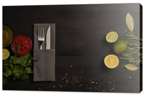 flat lay with cutlery, sauce, rosemary, spices and citrus fruits pieces on black tabletop