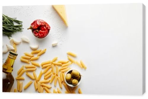 Top view of bottle of olive oil, pasta, cheese and ingredients on white background 