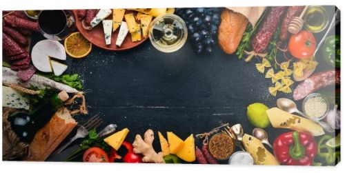 Assorted cheeses, sausages, wines, traditional spices and fresh vegetables on a wooden background. Cheese brie, blue cheese, gorgonzola, fuete, salami. Italian and Spanish Cuisine. Free space.