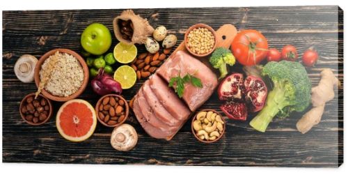 Healthy food. Raw meat, avocado, broccoli, fresh vegetables, nuts and fruits. On a wooden background. Top view. Copy space.