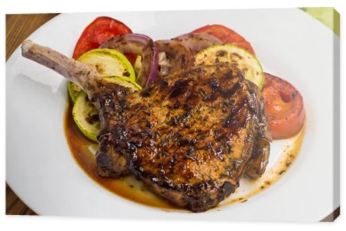 Pork steak on the bone grilled with vegetables. Wooden background. Top view. Close-up