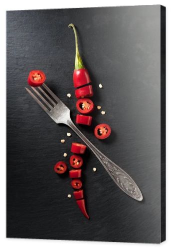 elevated view of cut red ripe chili pepper and fork on black surface