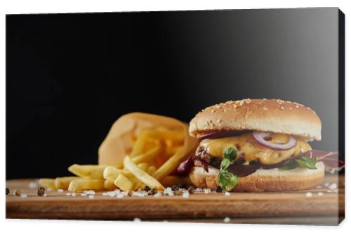 salt, french fries and delicious burger with meat on wooden surface isolated on black