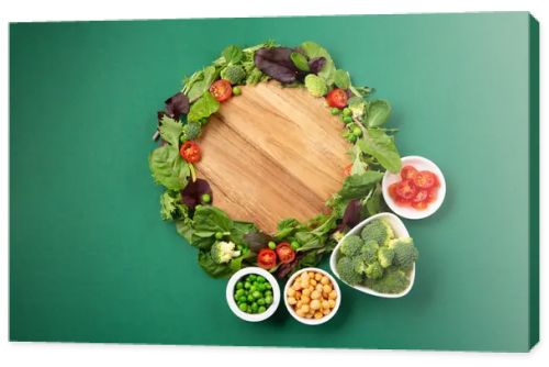 Vegetarian and vegan diet month in january called Veganuary. Variety of vegan, plant based protein food, healthy raw vegetables. Top view on green background.