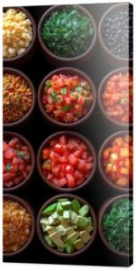 colorful spices, legumes, and foods in small bowls on a black surface